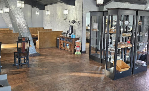 Interior of a cozy café featuring wooden tables, a display case with baked goods, and a welcoming atmosphere.